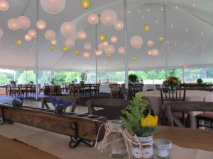Wood furniture and decor and cafe lighting, both inside and outside of the tent, help to meet the demand for rustic-themed events. Photo courtesy of Blue Peak Tents.