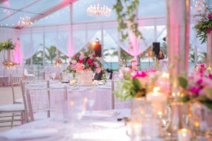 This wedding reception in a clearspan tent at Old Fort Bay, Nassau, the Bahamas, featured vibrant shades of pink in the florals and lighting, complemented by more traditional chandelier lighting. Event planner: Wildflowers Events & Occasions. Photo by Dennis Kwan Wedding Photography.