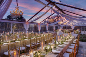 Caplan Miller Events set the tone for a wedding in Dripping Springs, Texas, with a custom ceiling, leg draping and valance, as well as with crystal chandeliers and amber ambient lighting. Photo by Jerry Hayes Photography.