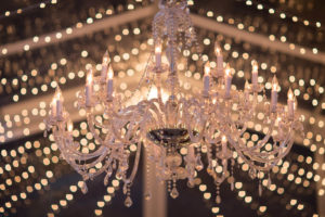 The couple wanted the feeling inside their reception tent to be warm and romantic. To that end, twinkle lighting was strung from the ceiling, accenting the chandeliers. Event planner: Wildflowers Events & Occasions. Photo by Philip Siciliano Photography.