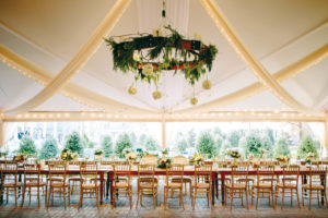 Custom draping with soft lighting, long feasting tables, elegant gold tones and wood components create a warm, intimate feel to this winter wedding by Party Reflections Special Event Rentals held in Raleigh, N.C. Photo by Katherine Miles Jones Photography.