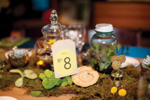 When a couple sought a green approach that included centerpieces that lived beyond their wedding, Bungalow 6 Design & Events planted small succulent gardens in glass apothecary jars for guests to take home. The rest of the table was covered with Spanish and reindeer moss, as well as petrified mushrooms. Photo by Studio 220 Photography.