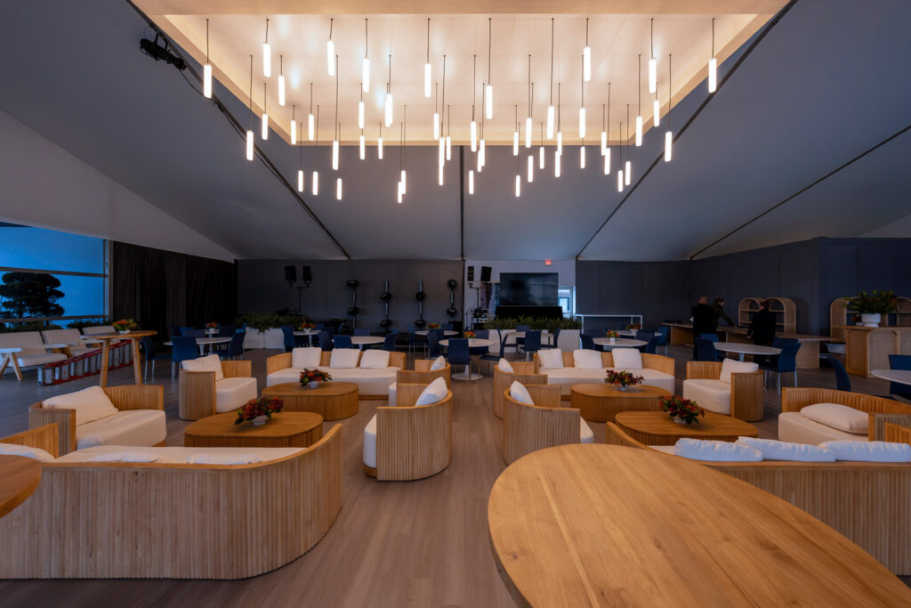 Modern lounge area featuring circular wooden seating and tables, under stylish pendant lighting, with a well-lit, inviting atmosphere.